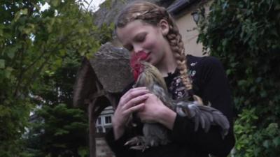 A young girl holding a chicken