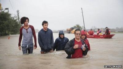 People make their way out of a flooded neighbourhood after it was inundated with rain water, remnants of Hurricane Harvey, on August 28, 2017 in Houston, Texas