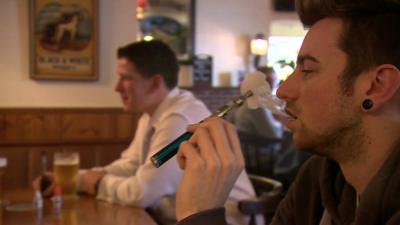 Young man in pub smoking e-cigarette