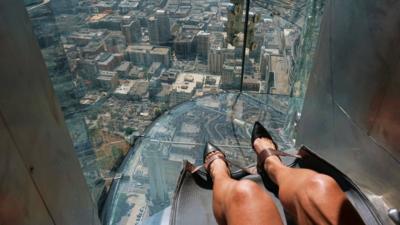 A rider at the top of a glass slide in Los Angeles