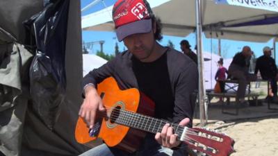 Samih playing a guitar in the Idomeni migrant camp.