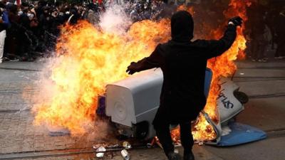 Protesters against Macron's pension reform set bins alight after two weeks of rubbish strikes.