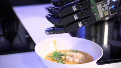 Moley - a robotic kitchen puts herbs on a crab dish it has prepared