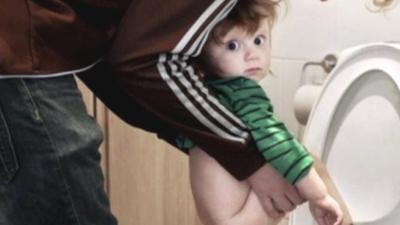 Man holding child over loo