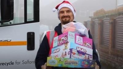 Sam Barry in a Santa hat with presents