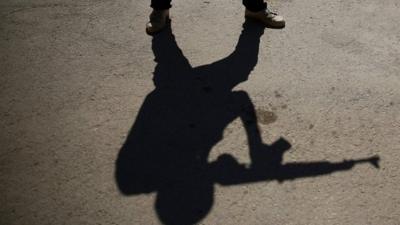 The shadows of rebel fighters carrying fake weapons