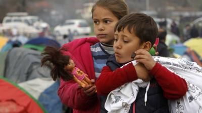 Refugee children walk through a makeshift camp at the northern Greek border post of Idomeni, 16 March 2016.