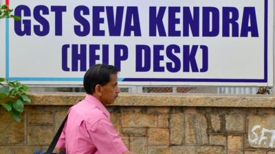 A pedestrian walks past a poster advertising about the new goods and services tax (GST) regime at the Service Tax Office in Bangalore on June 29, 2017.