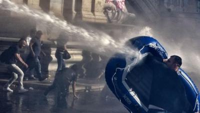 Protester uses inflatable boat to shield himself from water cannon in Rome