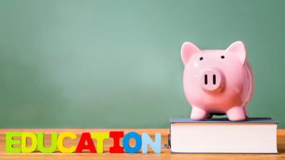 Piggy bank sat on book next to education sign