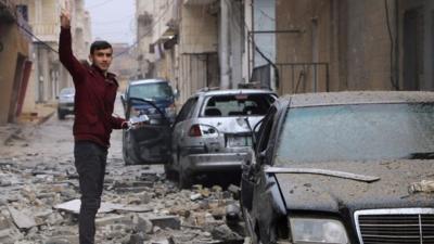 A man gestures while standing amidst debris in the Syrian Kurdish town of Jandairis in the northern Afrin district