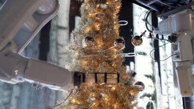 A robot decorates a Christmas tree