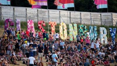 Crowds sitting in Glastonbury sunshine