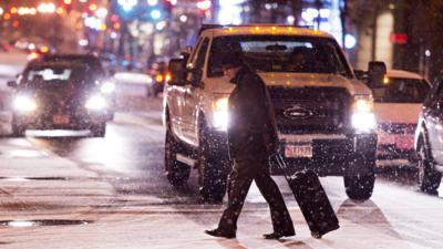 Man crosses the road in front of traffic with snow falling