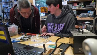 Two men repairing a mobile phone