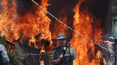 Police officer in front of flames from blast