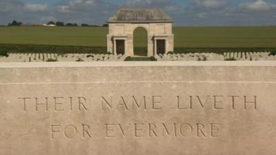 Graves of fallen soldiers behind a memorial