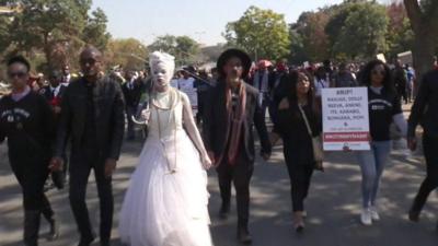 A woman clad in white leads marchers through Pretoria