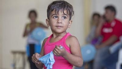 Syrian boy stands in warehouse in Cyprus