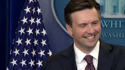 Press secretary Josh Earnest smiles as he speaks to journalists