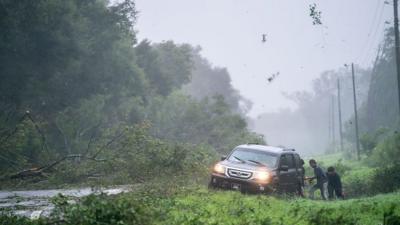 People work to free a vehicle stuck on the shoulder amid storm debris as Hurricane Idalia crosses Florida