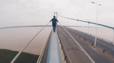 Man walking on bridge suspension cable