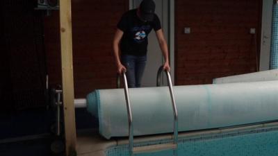 Man lowering a ladder into a pool