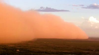 Orange dust cloud sweeping across ground