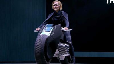 CGI of a woman riding a motorbike with no helmet
