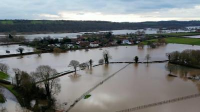 Nearby caravans can be seen surrounded by flood water