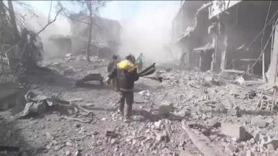 A rescue worker is pictured running through damaged street.