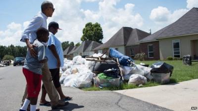 President Barack Obama walks with residents as he tours a flood-affected area in Baton Rouge, Louisiana.