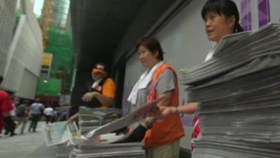 Women handing out newspapers in Hong Kong