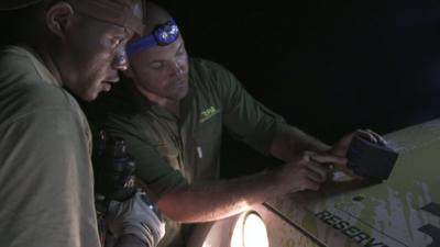 Two park rangers check gear ahead of patrol