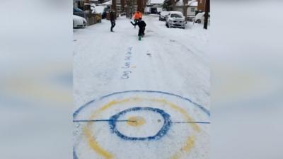 Friends took advantage of the snowy conditions to turn a road into a curling rink.