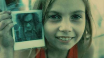 A young girl holding a shot of Wim Wenders