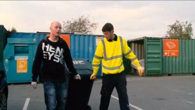 Junior Roberts (l) is shown how he can recycle more by the tip supervisor (r)