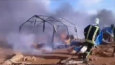 Firemen attempt to put out a burning tent