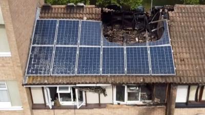 Aerial image of a fire-damaged house with a hole in its roof.