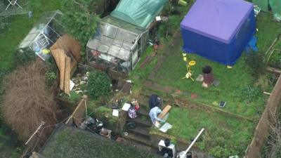 Aerial footage showing person in forensics suit in garden