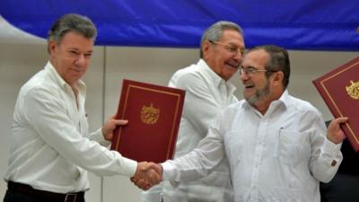 Colombian President Juan Manuel Santos and Farc leader Timochenko shake hands at the ceremony in Havana with Cuban President Raul Castro in the background.