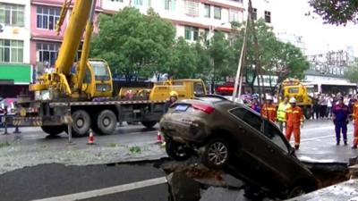 Crane pulls car out of hole