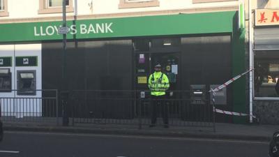 Police remain at the bank on Tuesday