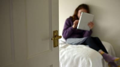 A girl uses social media in her bedroom