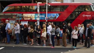 Early morning commuters form queues to board buses at Victoria station