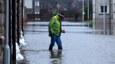 A man walks across a heavy flooded streets in Aboyne, in Scotland.