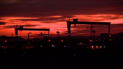 The Harland and Wolff shipyard cranes against a red sky backdrop