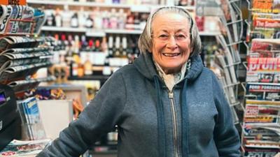 May standing by the counter in her shop