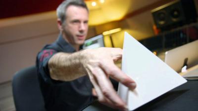 Spencer Kelly holds a tetrahedron to play an instrument called The Pulse