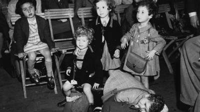 Children with suitcases waiting to be collected